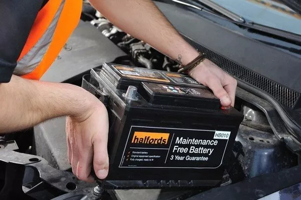 A picture of a man installing a new car battery.