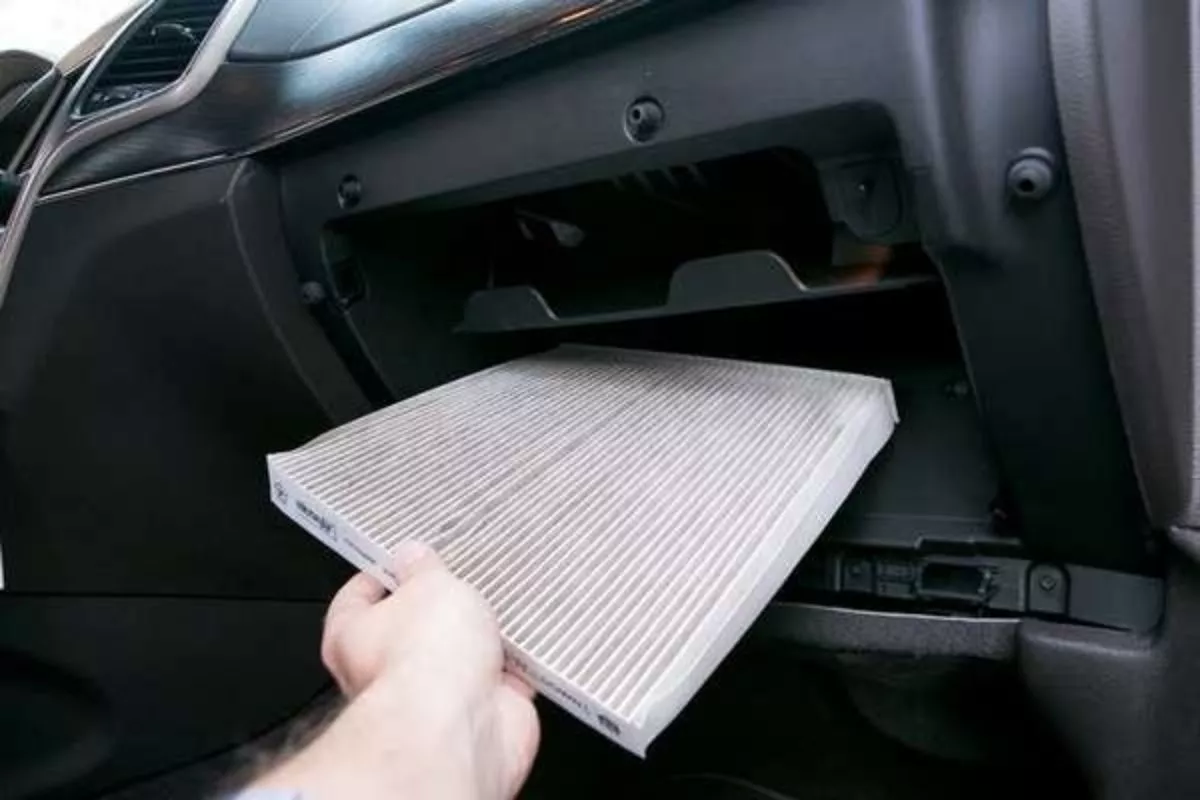 A picture of a person pulling out a cabin air filter from its box
