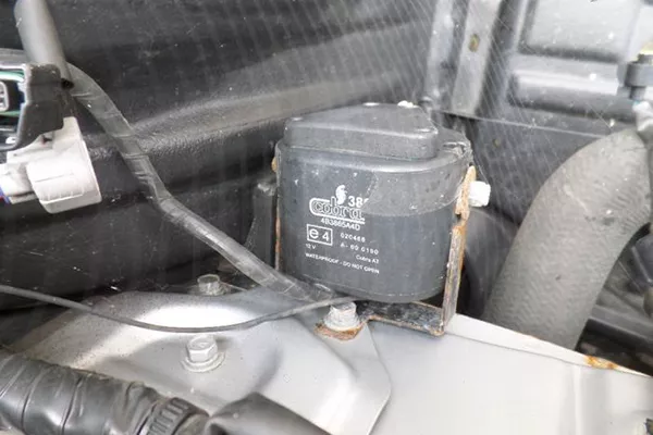 A picture of a car alarm siren mounted in the engine bay.