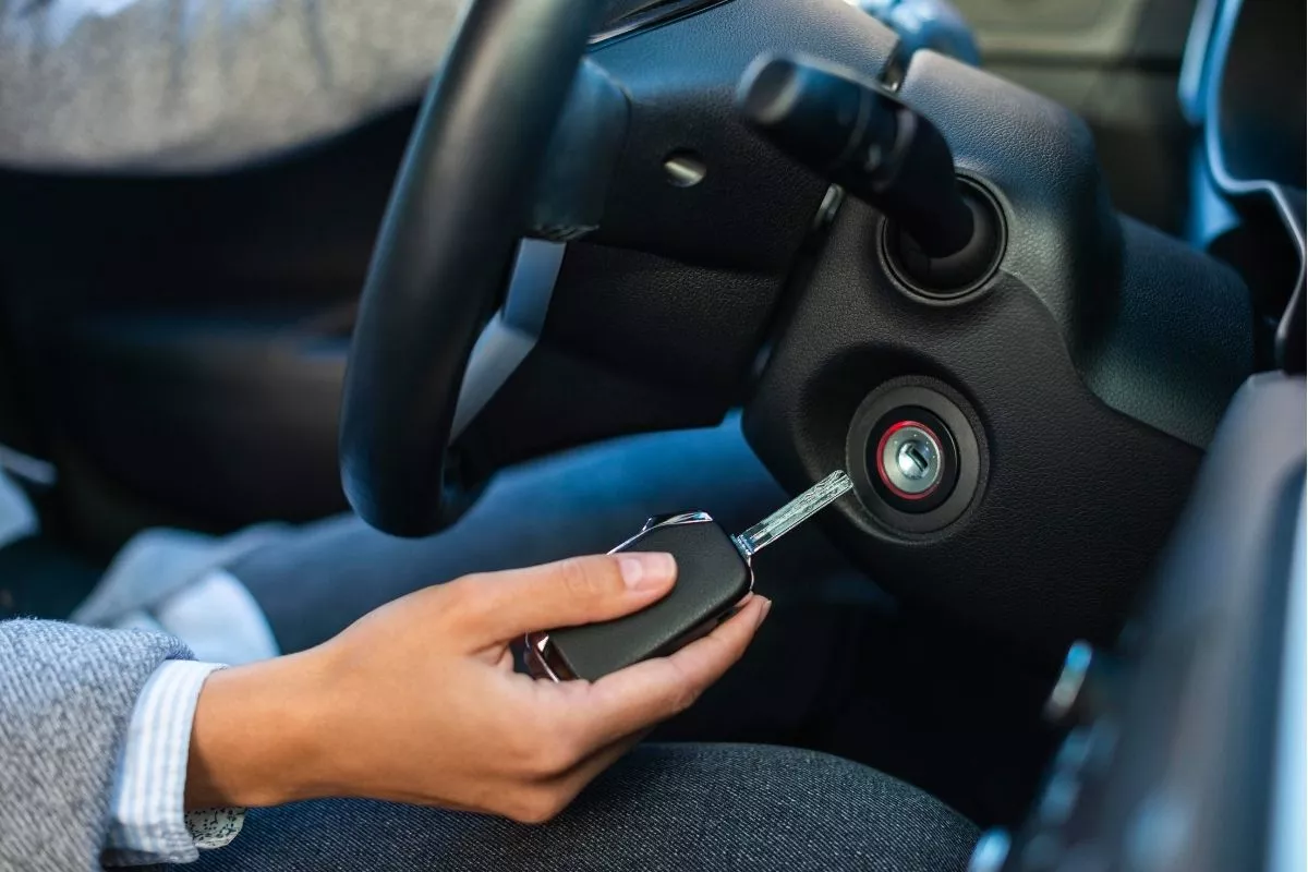 A picture of a person about to insert a car key into the ignition switch