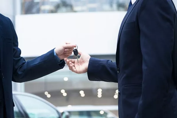 Man giving the car key to another person