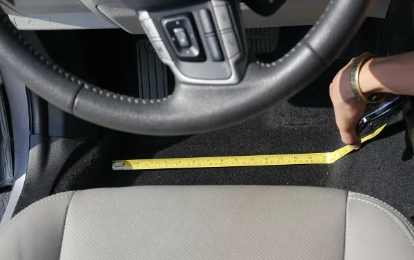 Measure the distance from the door to the center divider. man measuring the car floor