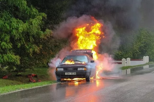 A picture of a car parked on the side of the road, on fire