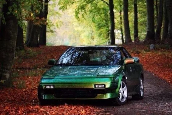 A picture of a green Toyota MR2 in the woods