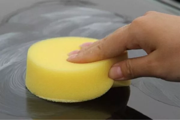 A picture of a man waxing his car.