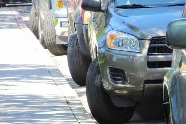 A picture of several cars properly parked downhill.
