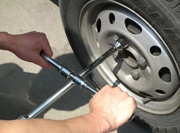 man using lug wrench to loosen the lug nuts