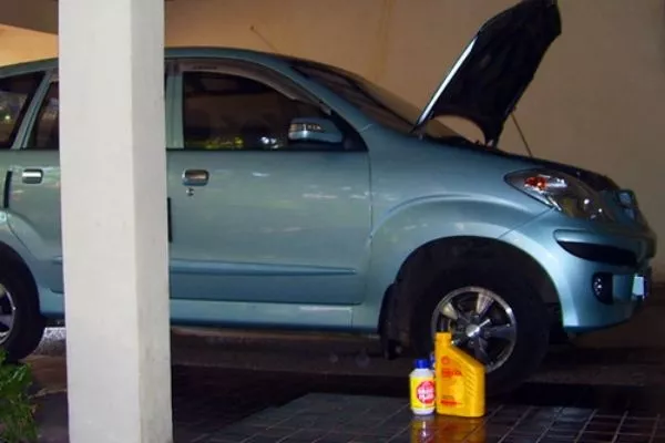 Don't forget to top of those fluids A picture of a parked car next to some essential car fluids