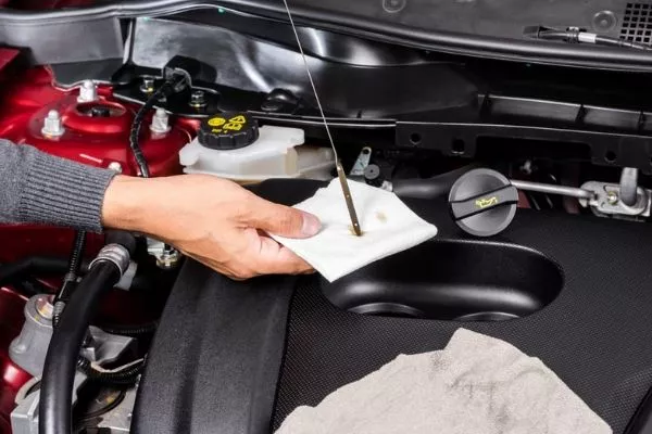 A picture of a man checking his car's oil levels.