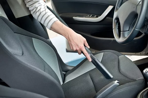 Woman vacuuming the car interior