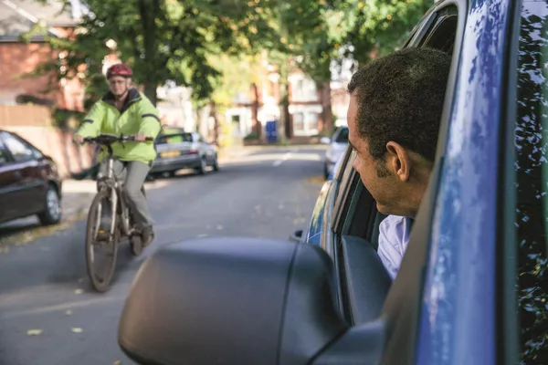 It's a must that drivers check their side mirrors and blind spot before they set off from a fixed position. Man checking the cyclist