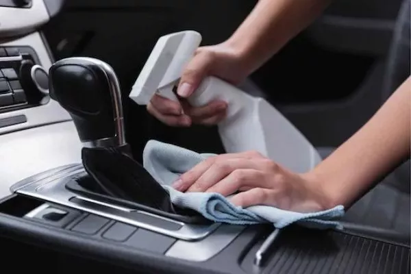 A picture of a woman cleaning her car using alcohol spray.