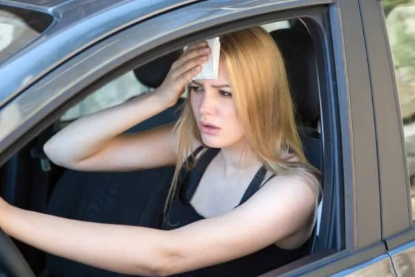 A picture of a woman sweating while driving