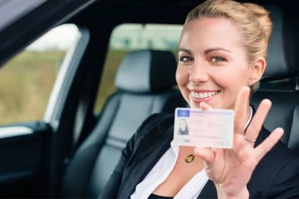 A picture of a driver showing her license.