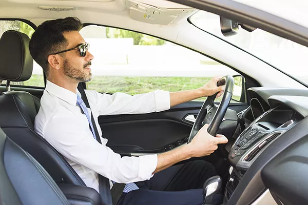 A picture of a man wearing sunglasses while driving.