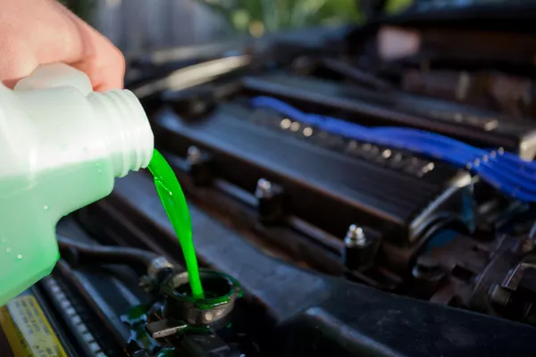 Make sure that your car always has a good amount of coolant Man putting coolant in the car's engine