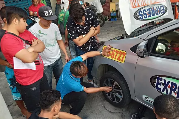 An Express Driving School instructor showing students how to change a tire Express Driving School in Valenzuela City