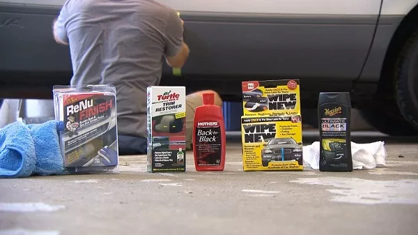 Man cleaning the car's finish and some cleaning materials