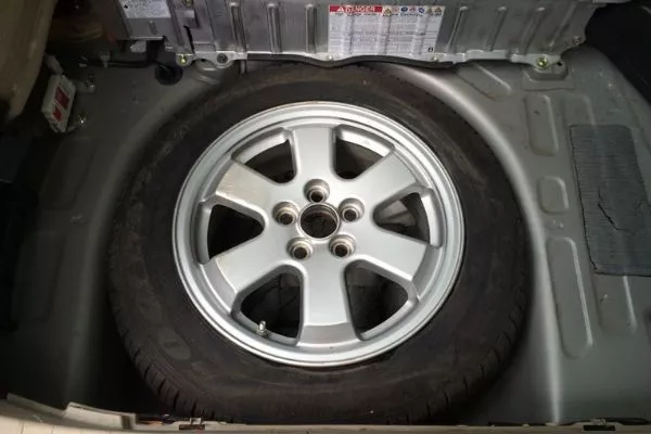 A picture of a full size tire inside a car's trunk