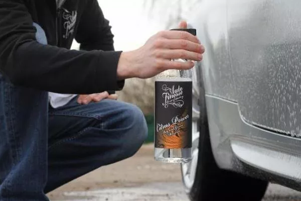 A picture of a man applying soap on a car.