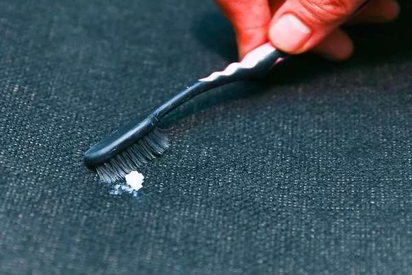 Man using brush to remove the gum on the car seat