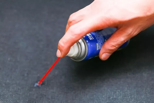 Man using the degreaser to remove gum on the car seat