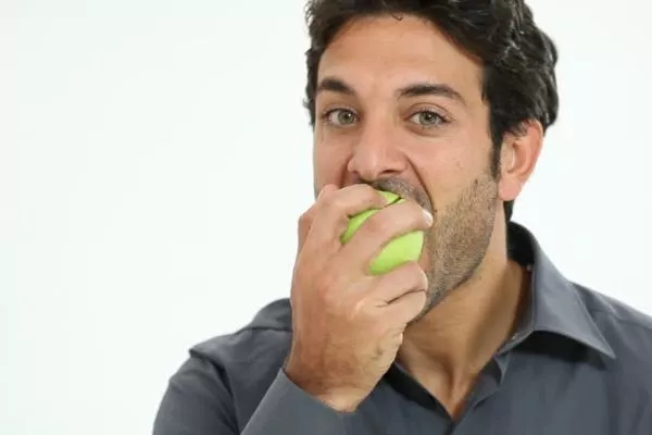 A picture of a man eating a green apple