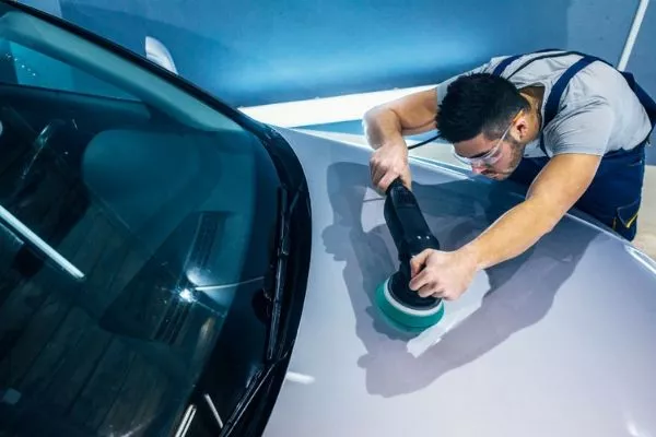 A picture of a man polishing a car