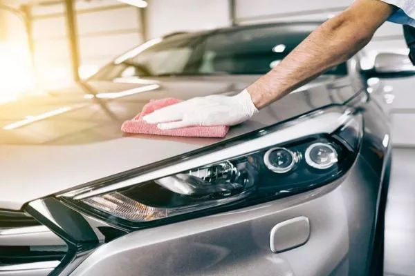 A picture of a guy waxing his car