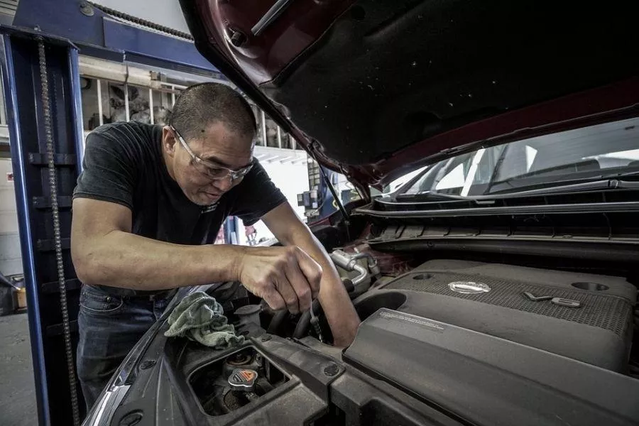 A picture of a man checking his car oil levels.