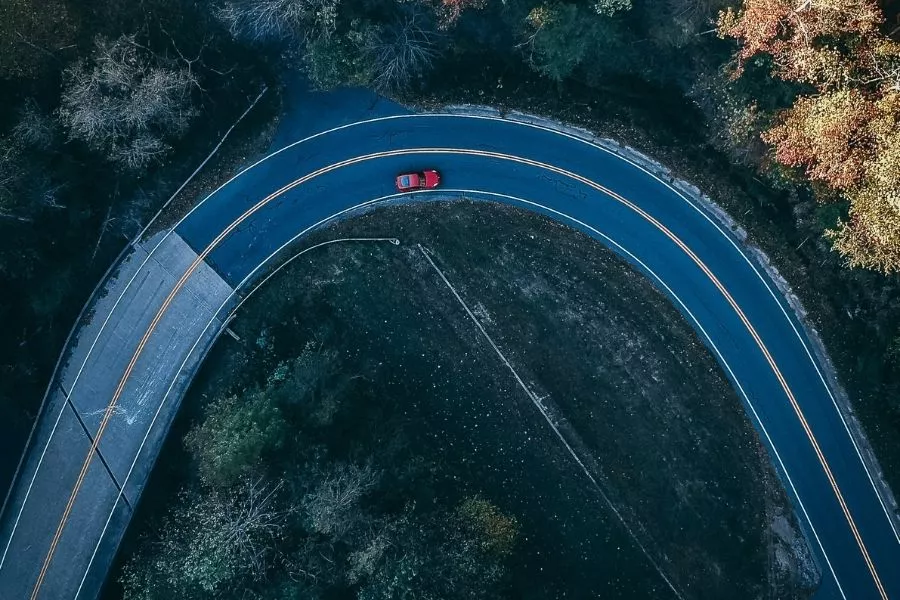 A curved road with a red car