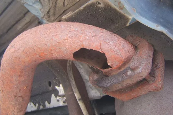 A picture of a rusty exhaust pipe with a hole on it