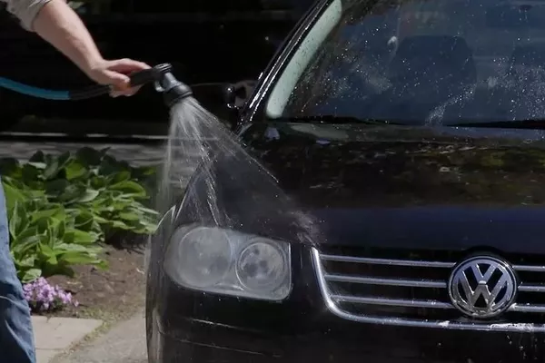 Rinsing car exterior thoroughly using a hose 