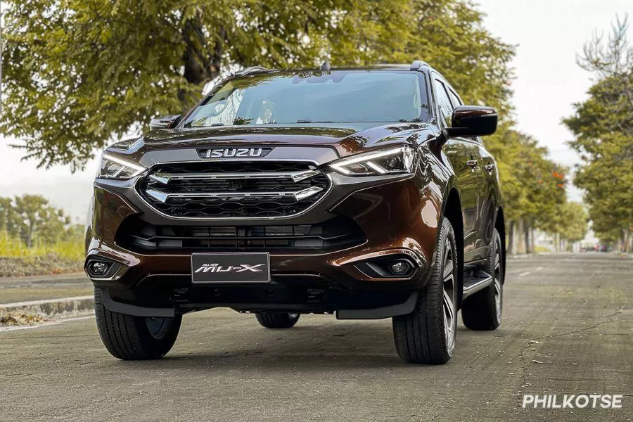 A picture of the new Isuzu mu-X on a road surrounded by trees.