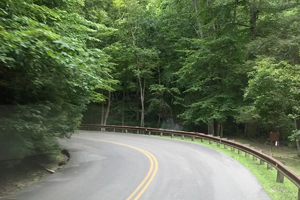 A picture of a road with a blind curve with double solid yellow lines.