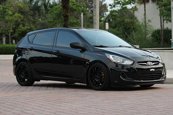 A picture of a Hyundai Accent with coilovers, aftermarket wheels, and tires.