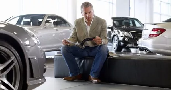 Man reading book near cars
