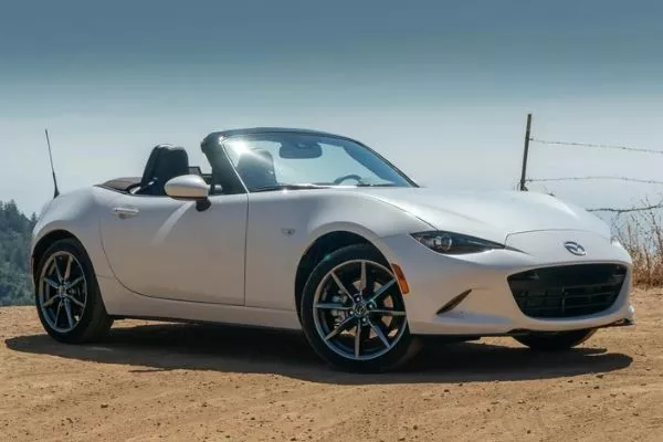 Essentially a car that's happy to see you A picture of a white Mazda Miata parked in a dusty, dry area