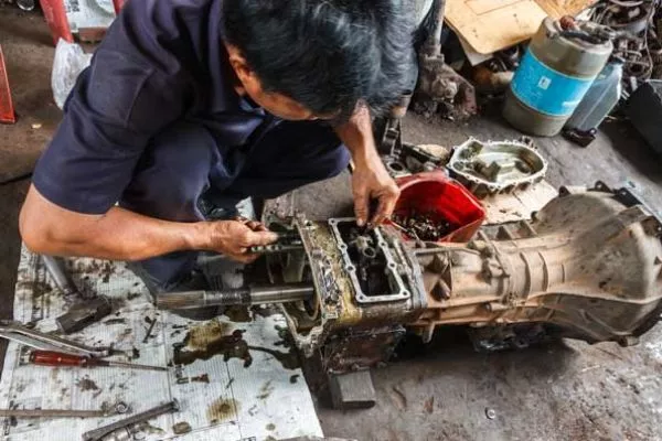 A picture of a man repairing a transmission