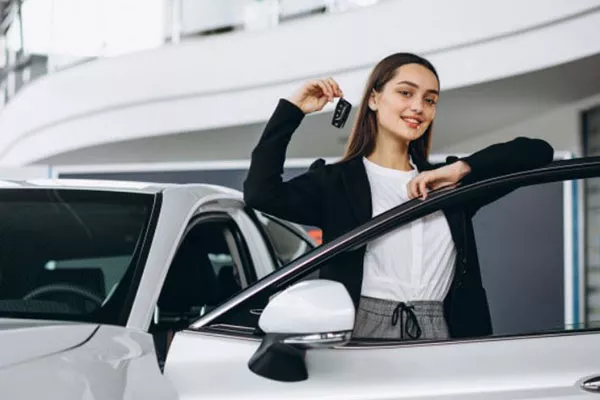 A picture of a young woman with her new car.