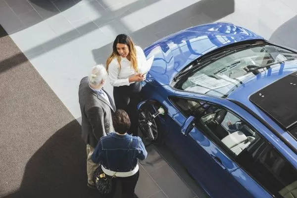 Car salesperson taking to an old man