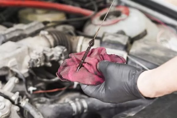 A picture of a man checking his car's oil