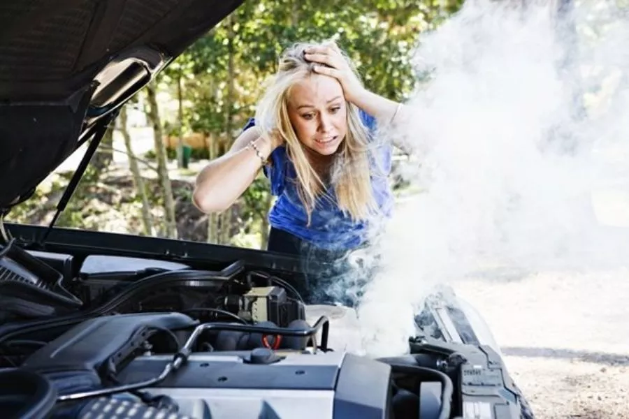 A picture of a woman panicking over an overheating car