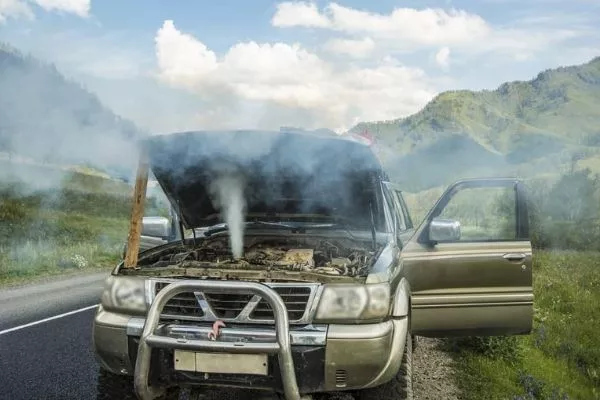 A picture of an overheating vehicle with mountains as a backdrop