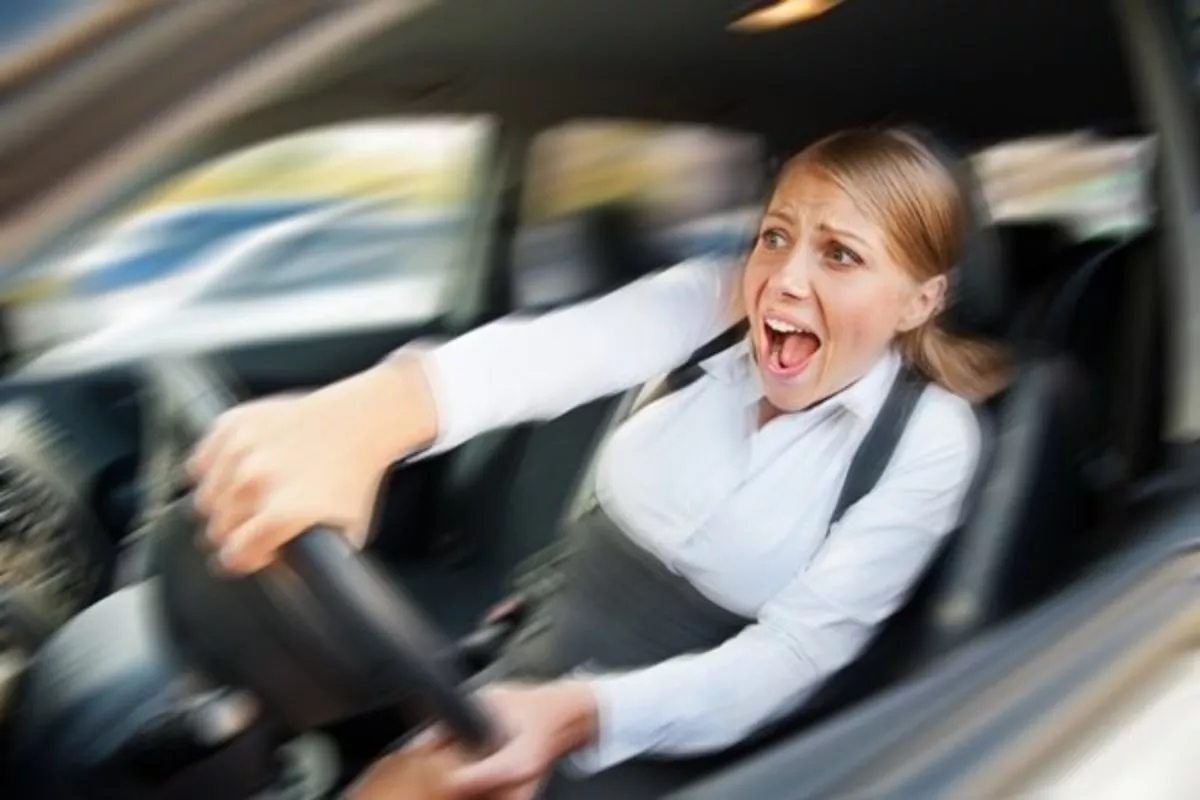 A picture of a woman grimacing while driving a car