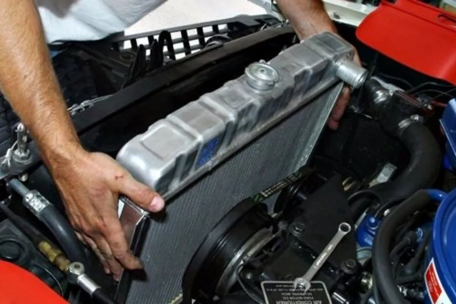 Man holding a radiator in an engine bay