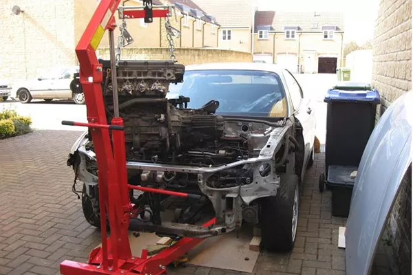 A picture of an engine crane lifting an engine out of a car