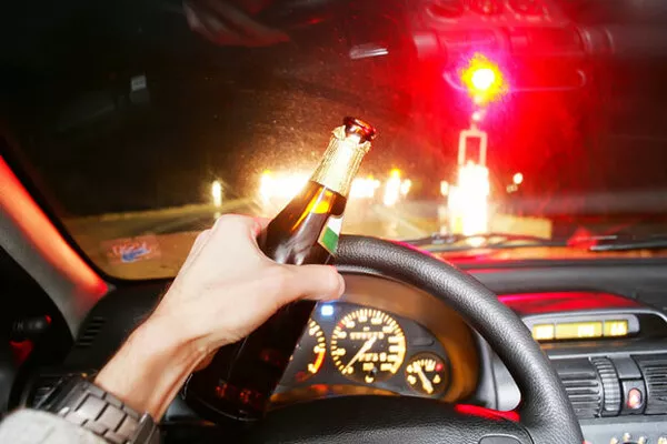 Driver holding a glass of liquor 
