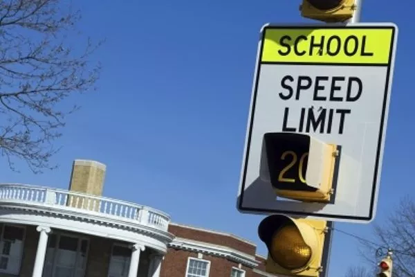 A sign of School Zone Ahead with a traffic light