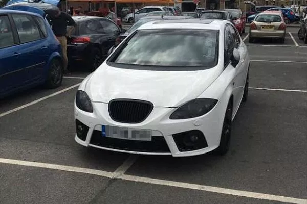 A picture of a car taking up four parking spaces.